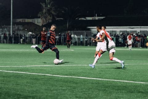 A Hope FC player striking the ball during a night match